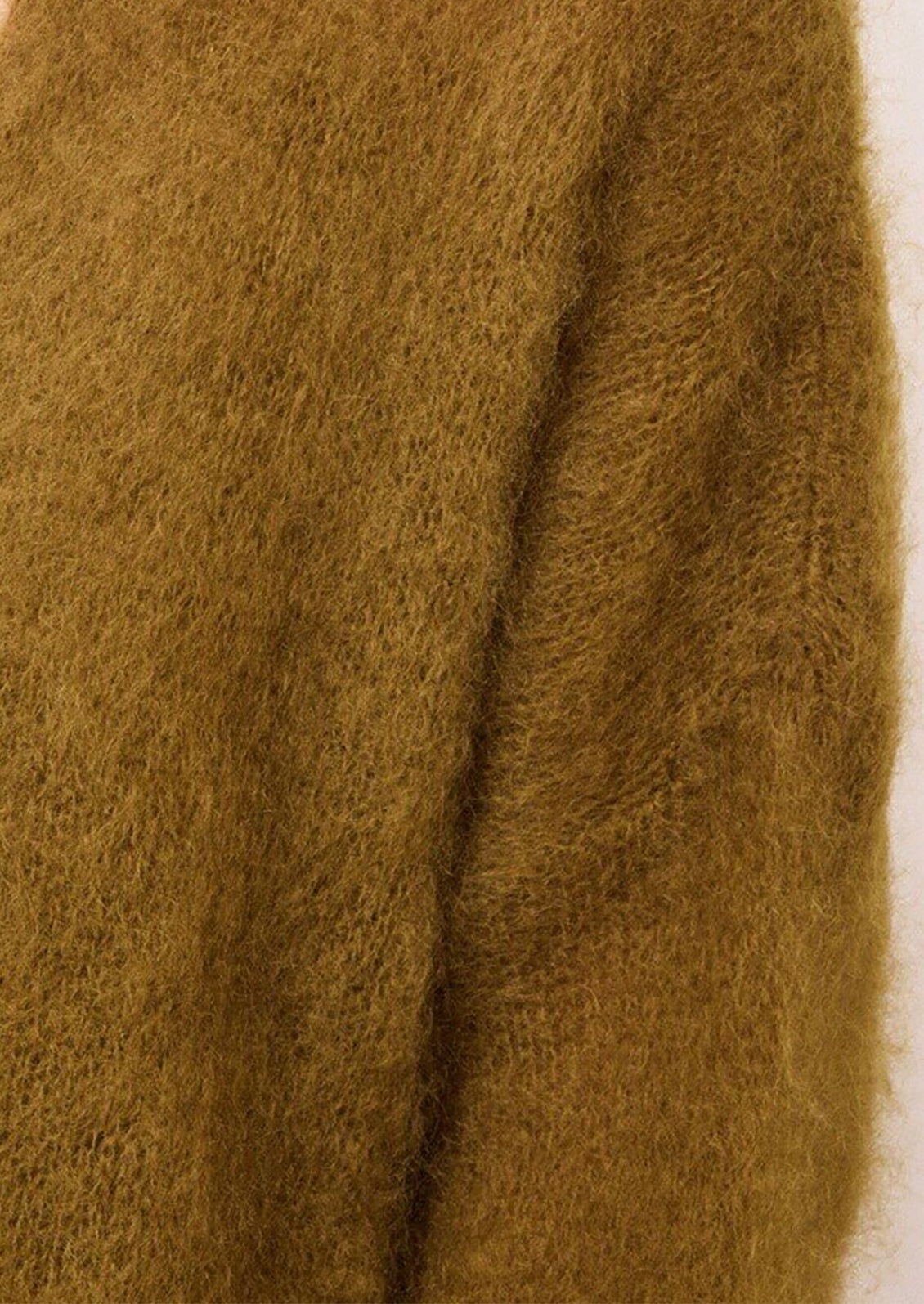 A close-up of a fuzzy, mohair-like garment in a warm mustard or ochre brown color, showing the soft, textured fabric.