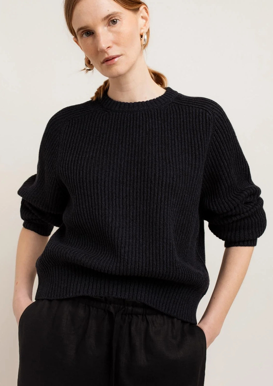 A person wearing a chunky rib knit sweater in black.