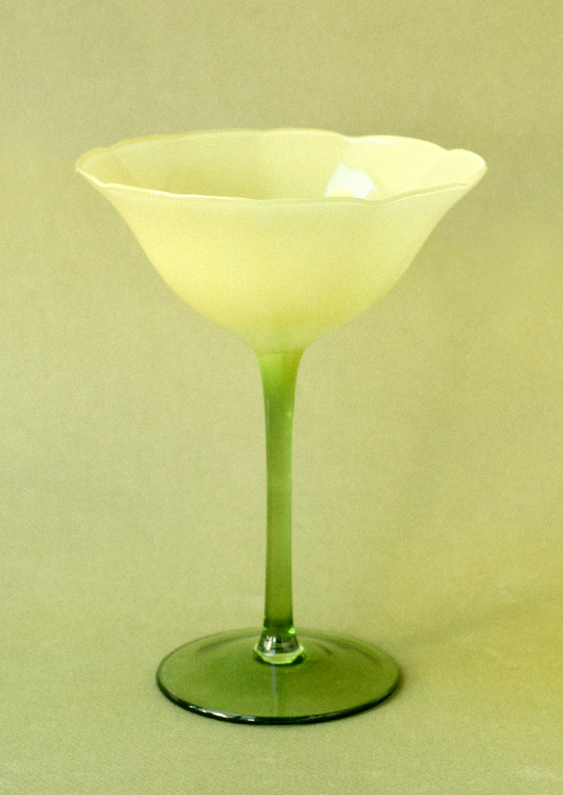 A coupe glass in the shape of a flower with a yellow top and green bottom.