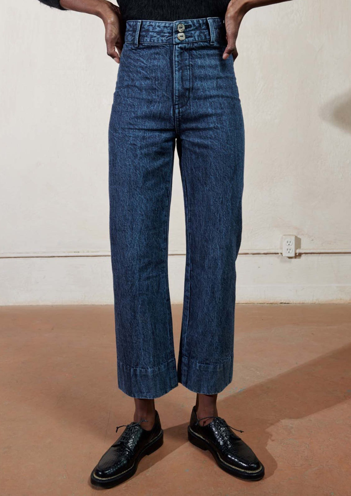 Woman wearing blue jeans and black oxfords.