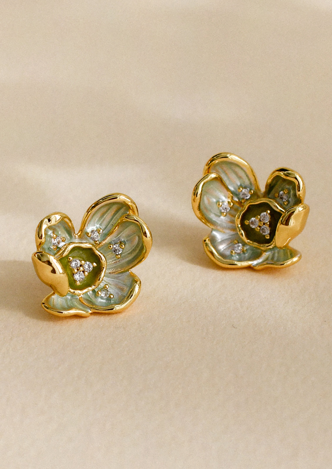 A pair of earrings in the shape of a flower in green enamel with crystal detailing.