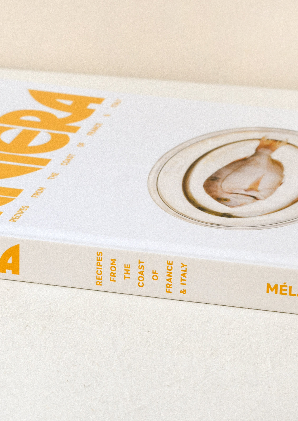 Side view of a cookbook titled 'Riviera - Recipes from the Coast of France & Italy' by Melanie Masarin.