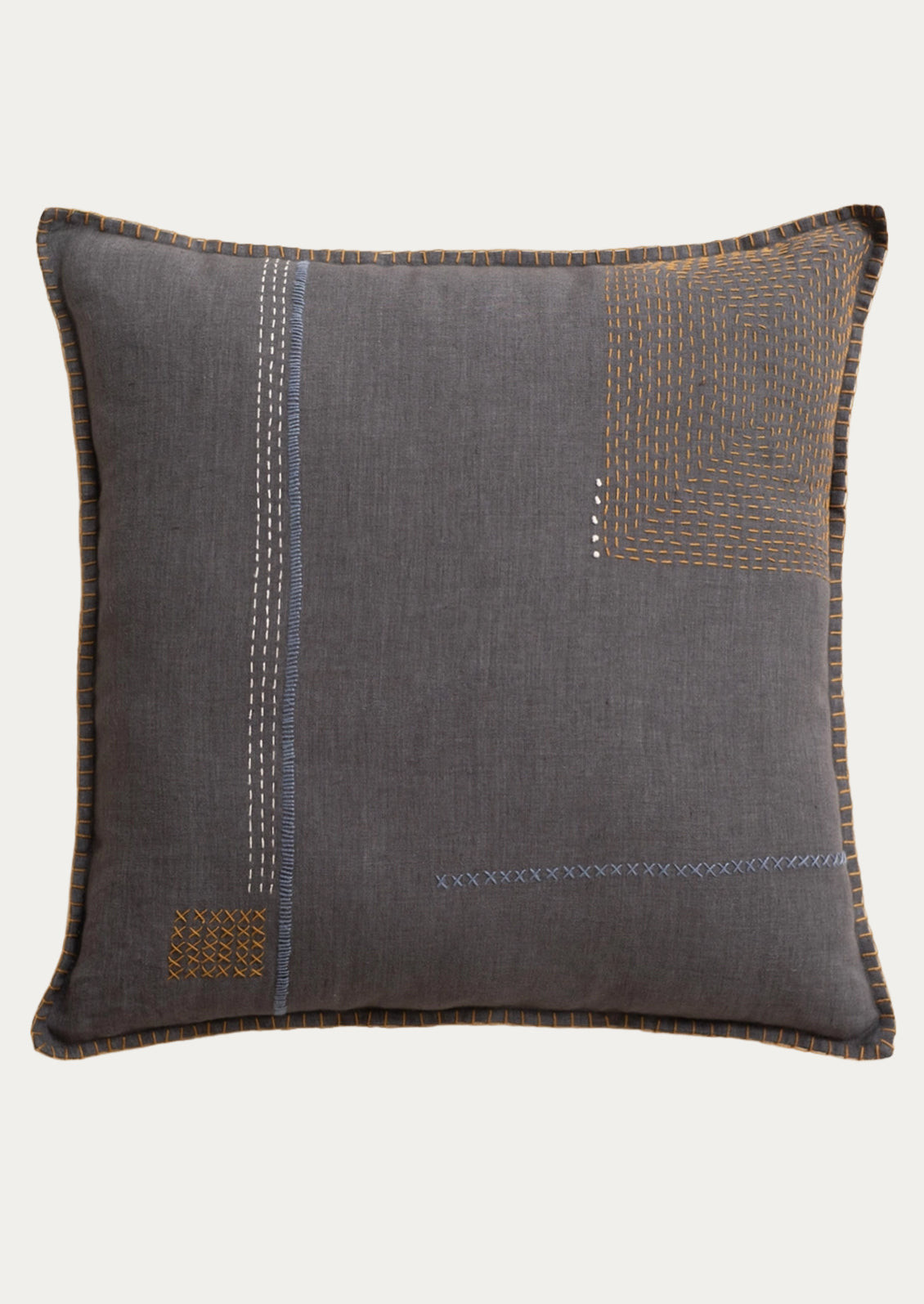 A charcoal linen pillow with decorative sashiko embroidery in white, slate blue and brown.