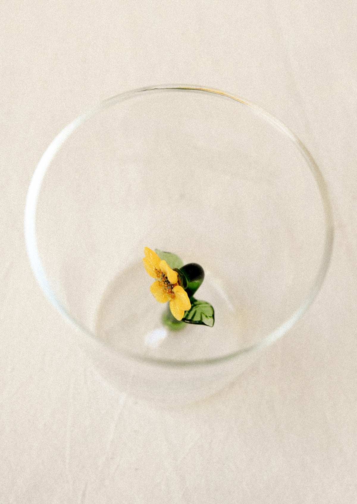 Clear drinking glass with a yellow sunflower charm inside glass.