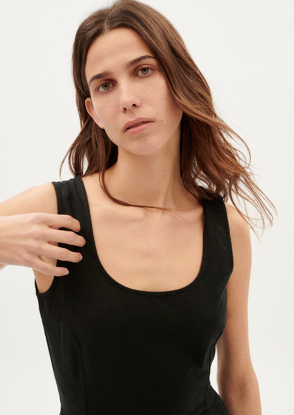 A woman wearing a black one piece jumpsuit with scoop neck.