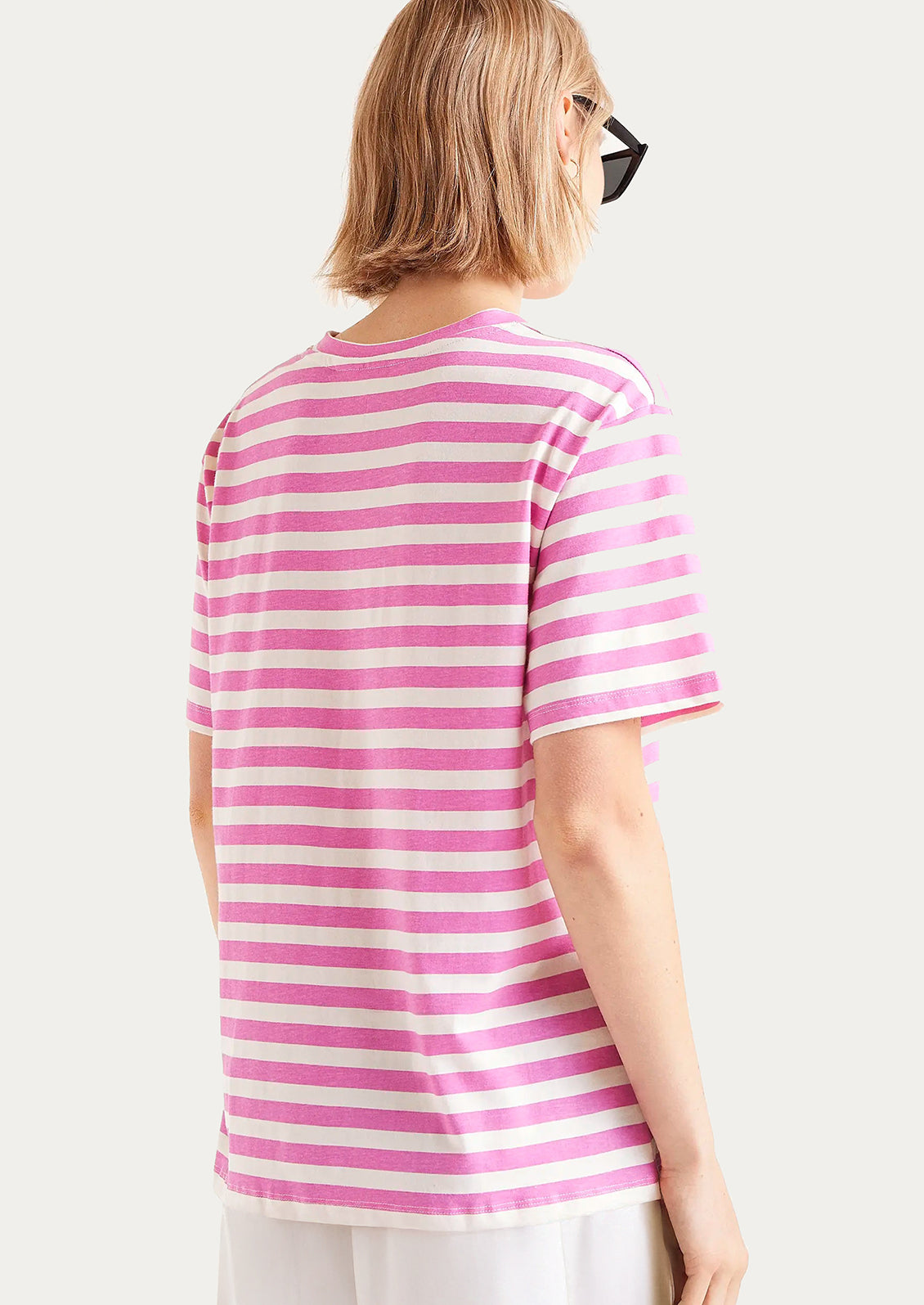 A woman wearing a striped short sleeve t-shirt in pink and white.