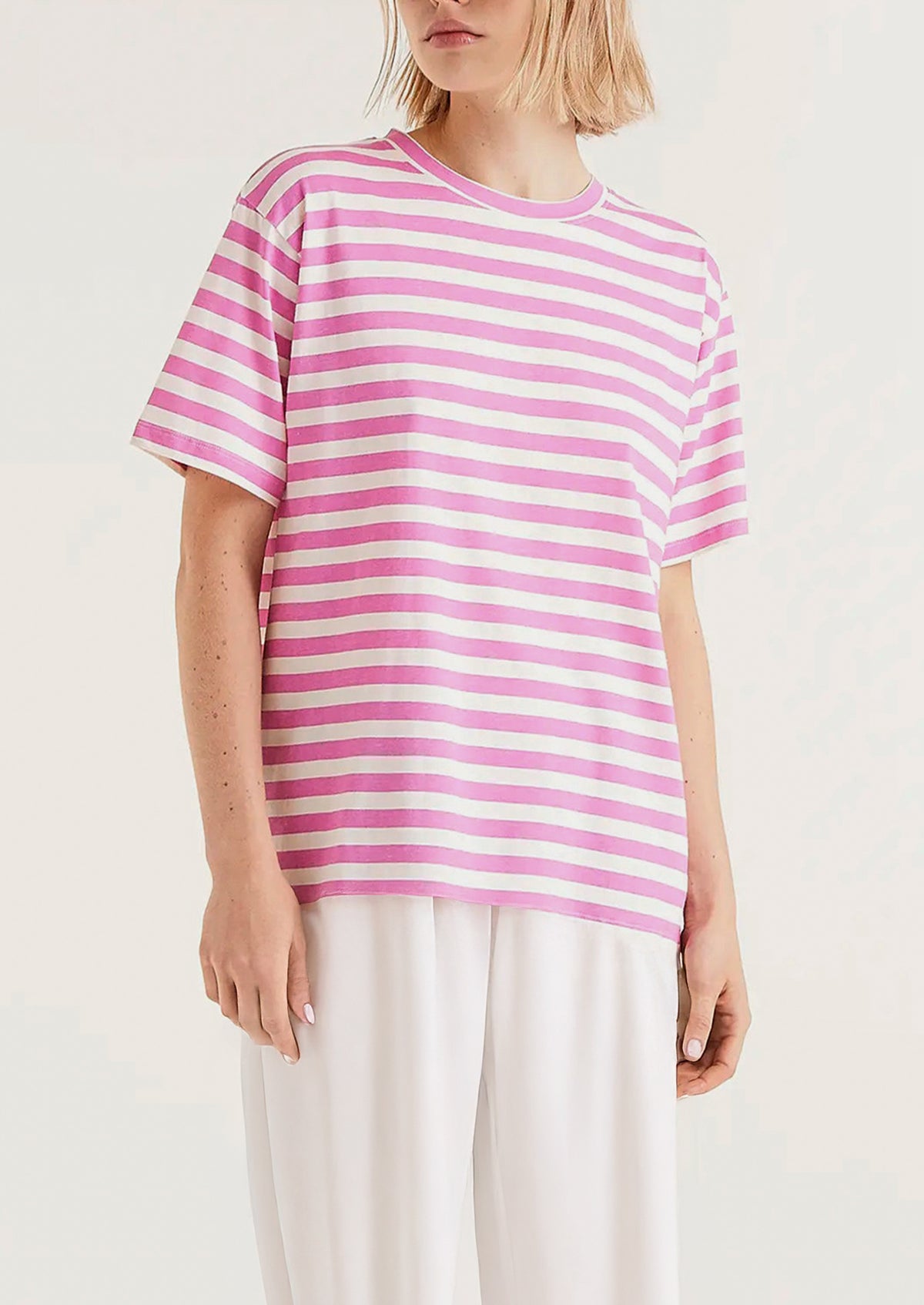 A woman wearing a striped short sleeve t-shirt in pink and white.