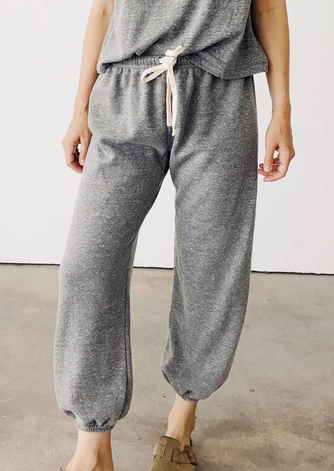A person wearing a pair of elastic bottom sweatpants in heather grey.