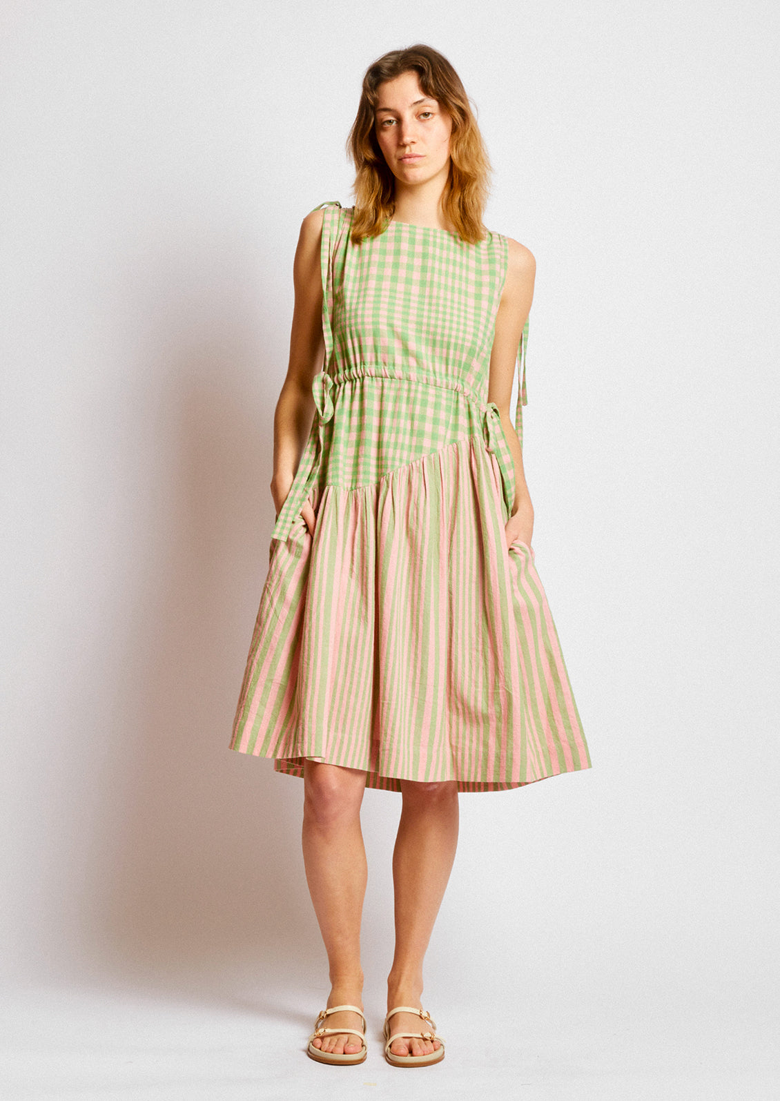 A person wearing a short dress in green and pink striped mix stripe and gingham.