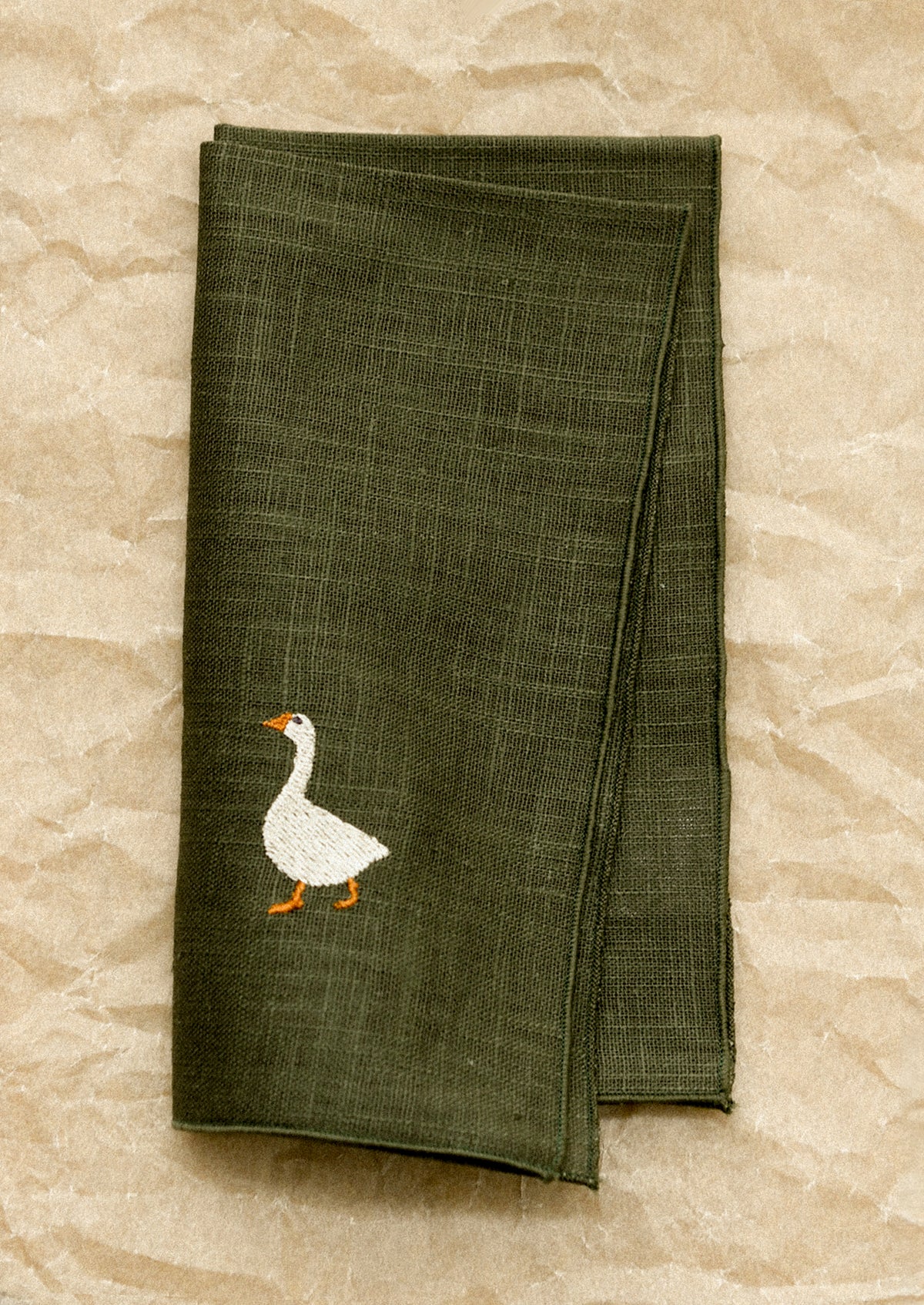 Green napkin with a goose design on a stone surface