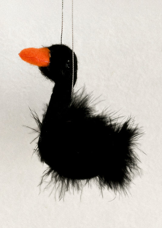 A black fluffy bird-shaped hanging ornament with a bright orange beak.