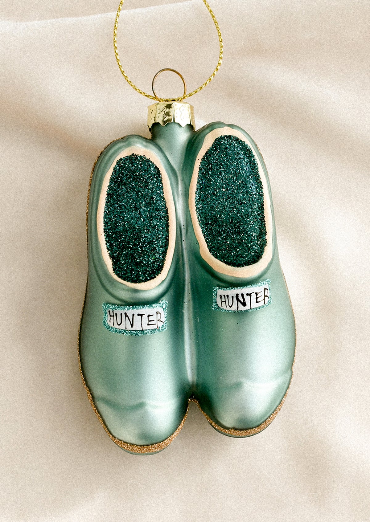 A decorative glass ornament depicting a pair of green garden clog shoes.