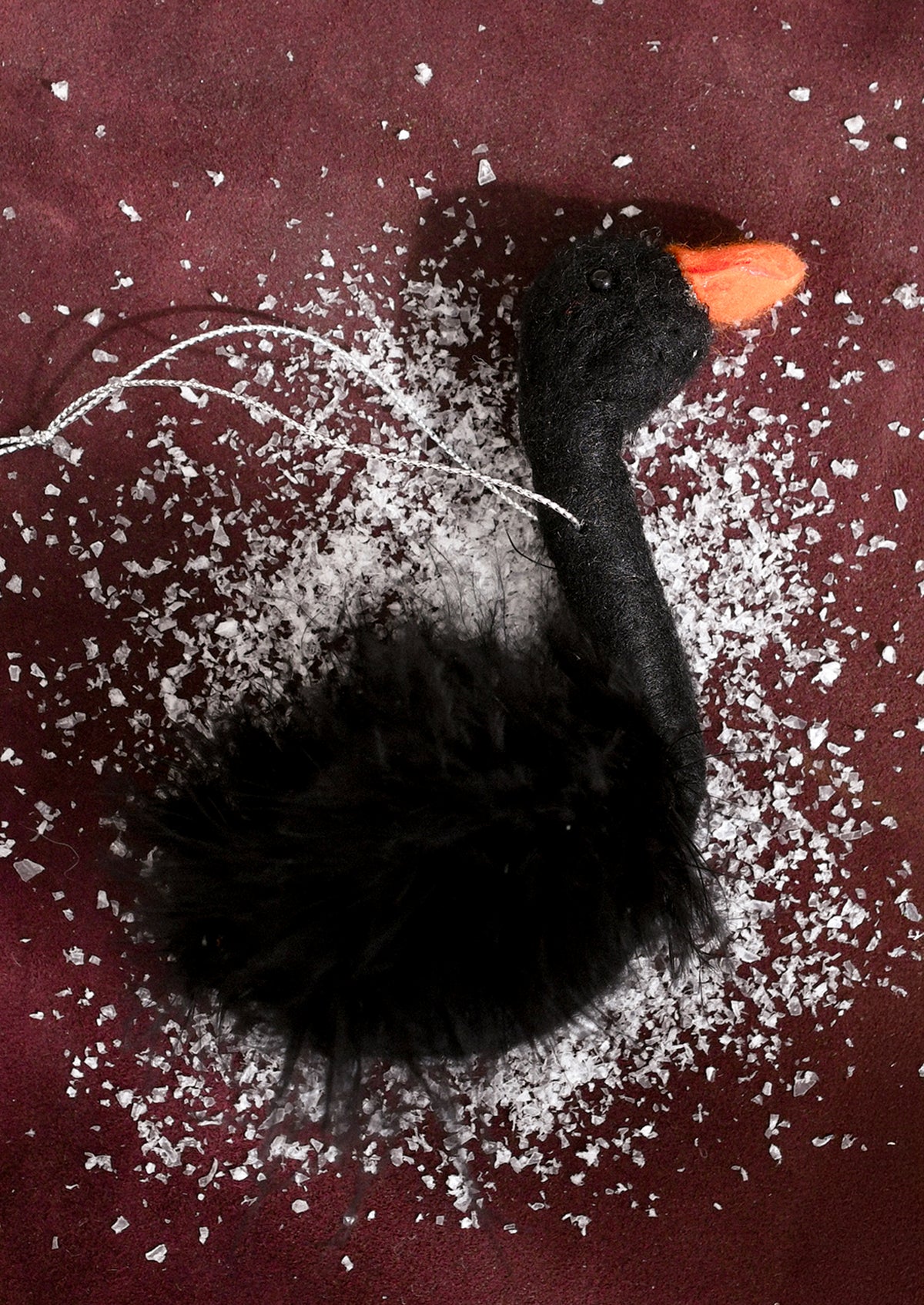 A black fluffy bird-shaped hanging ornament with a bright orange beak.