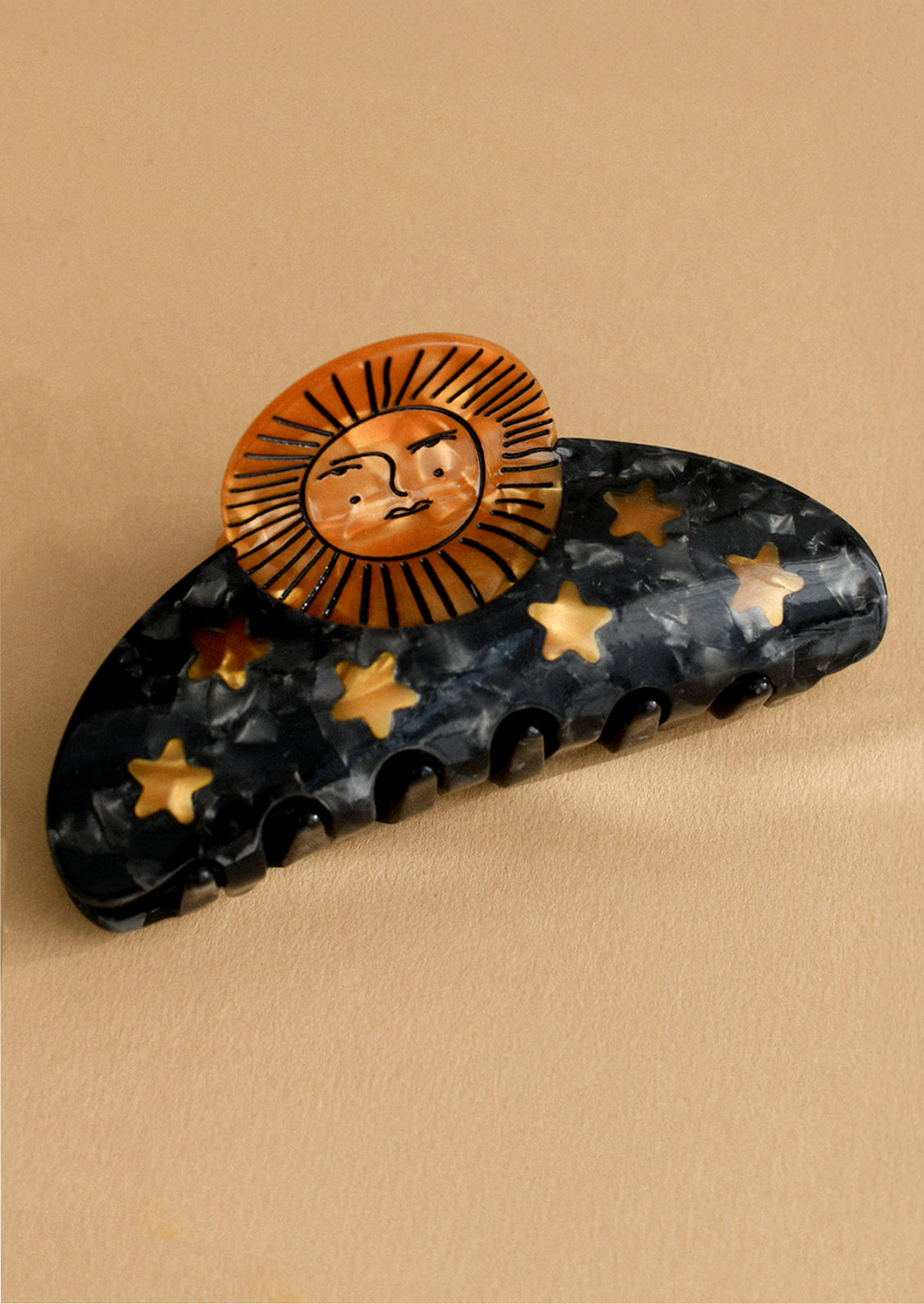 A black hair claw with copper sun and star pattern.