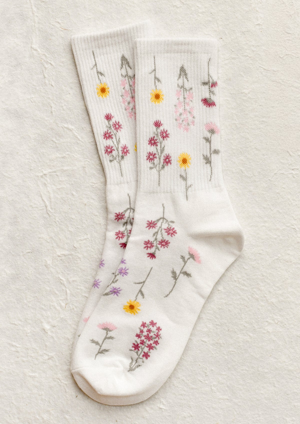 A pair of white socks with pink and yellow flower pattern.