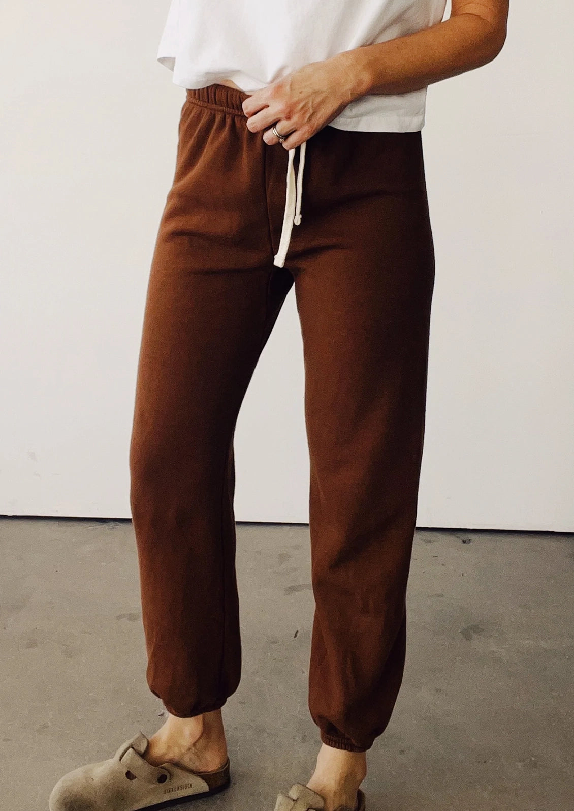A person wearing a pair of elastic bottom sweatpants in cedar brown.