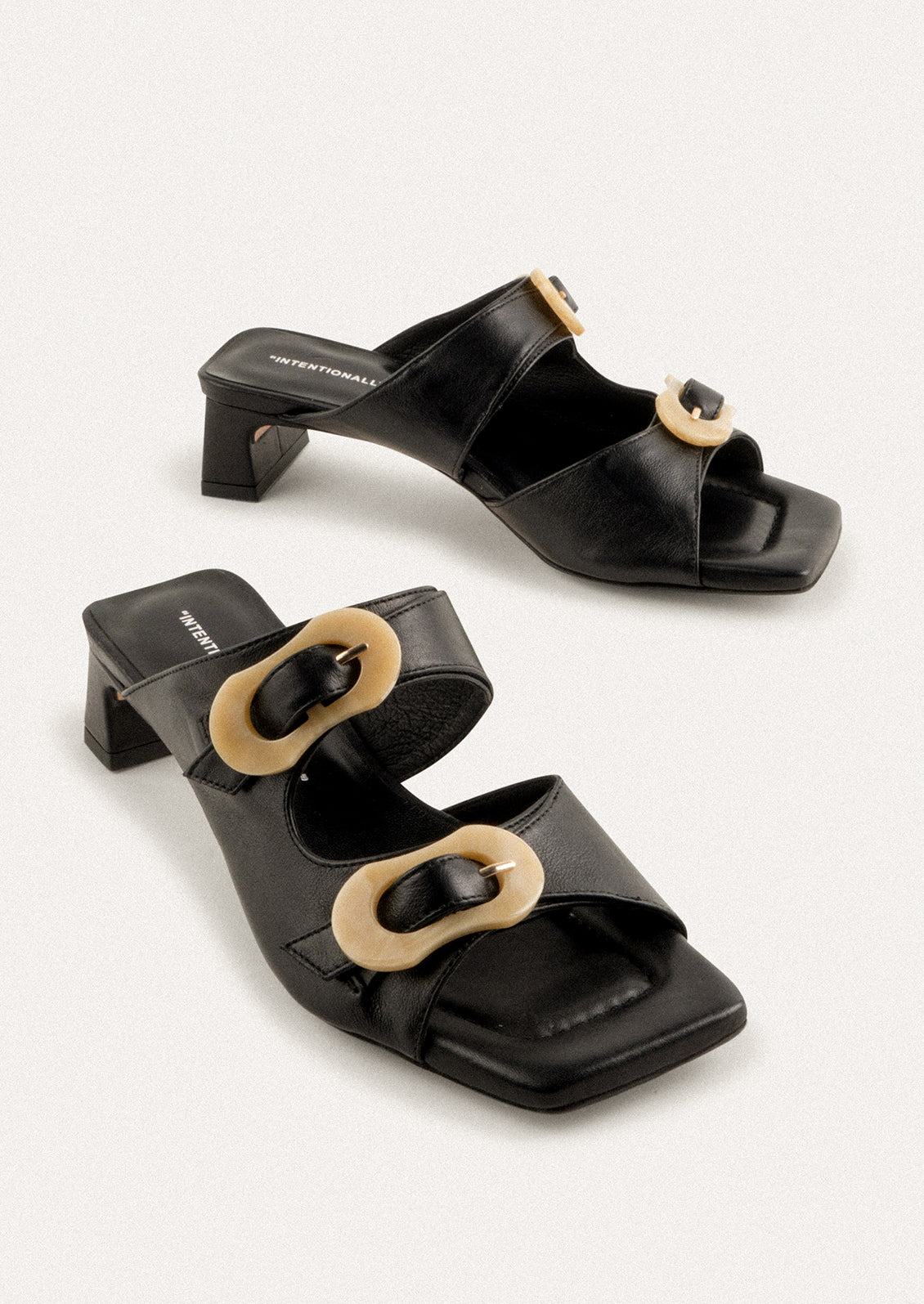 A square toe heeled sandal in black with double tan buckle detail.