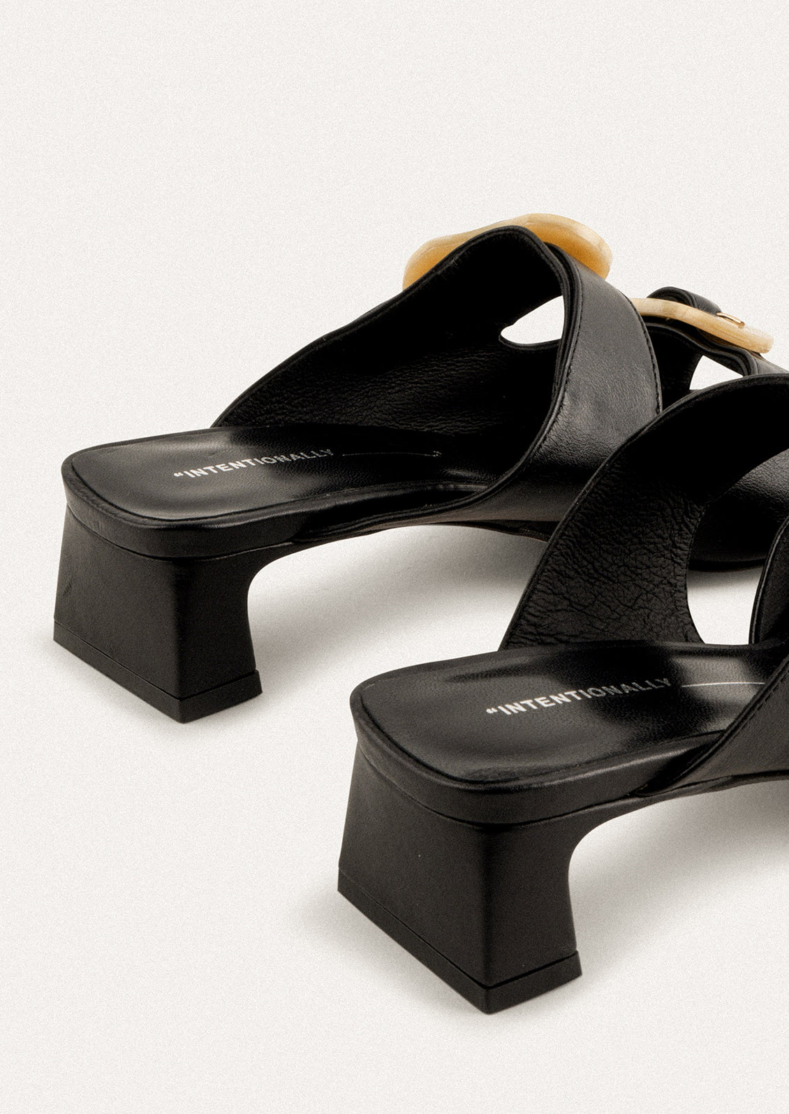 A square toe heeled sandal in black with double tan buckle detail.