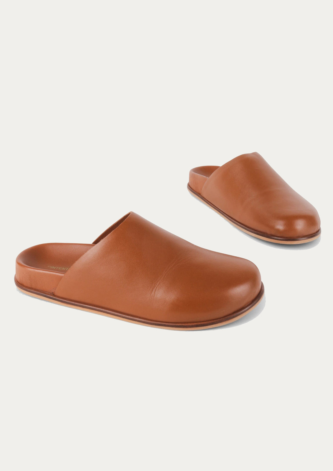 A pair of caramel leather closed toe slip-on mule shoes.