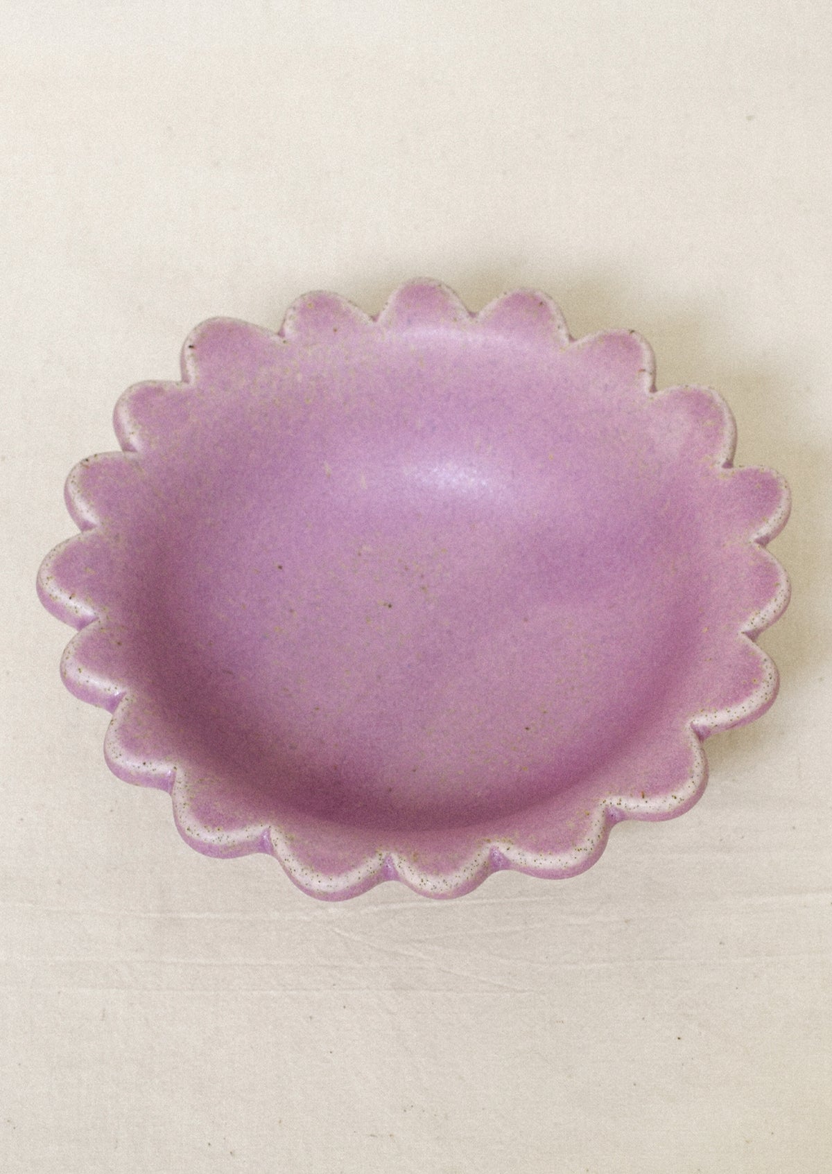 A ceramic scalloped edge bowl in a lilac color.