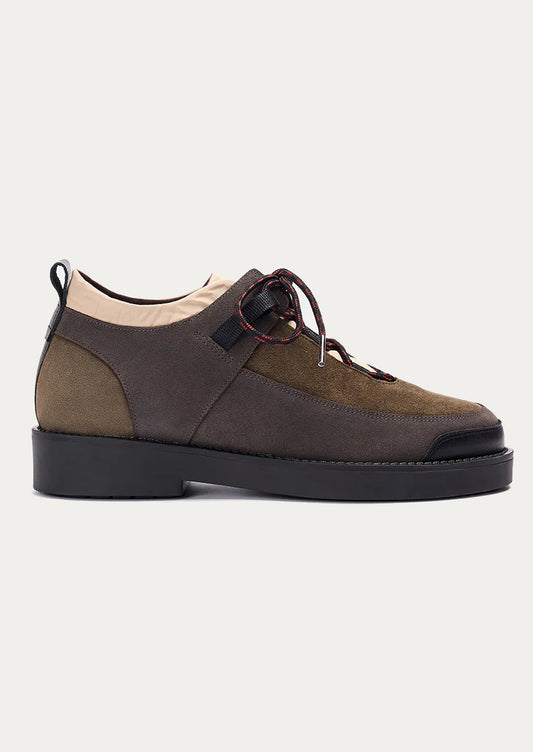 Brown suede shoe with black sole on a light gray background