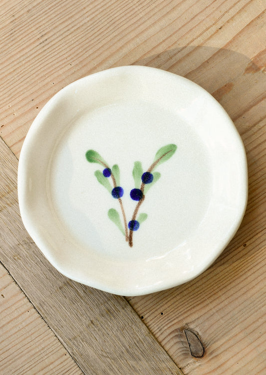 A small ceramic dipping fish with a watercolor illustration of blueberries on leafy branches in the center.