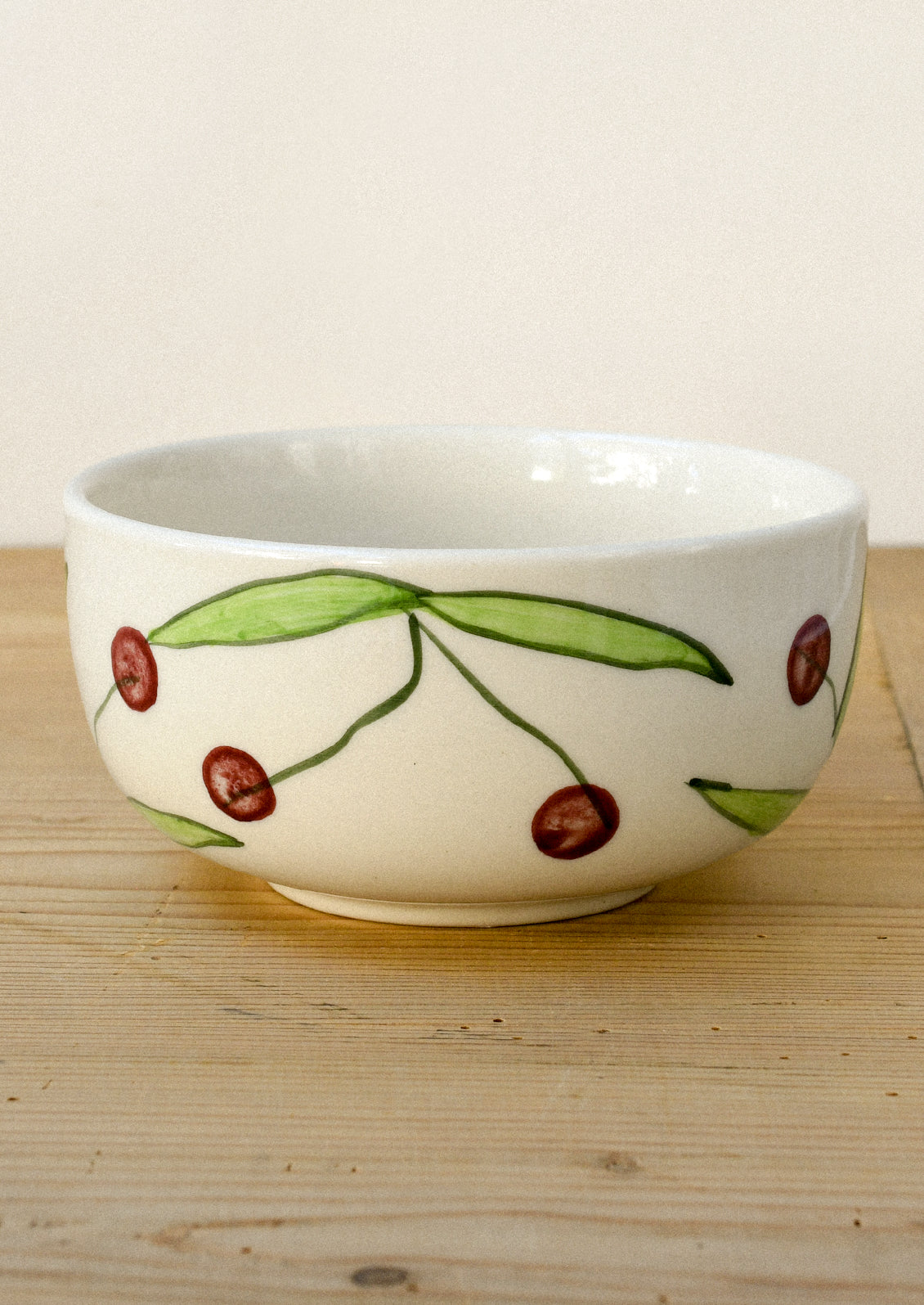 A ceramic bowl with a hand drawn illustration of black cherries.
