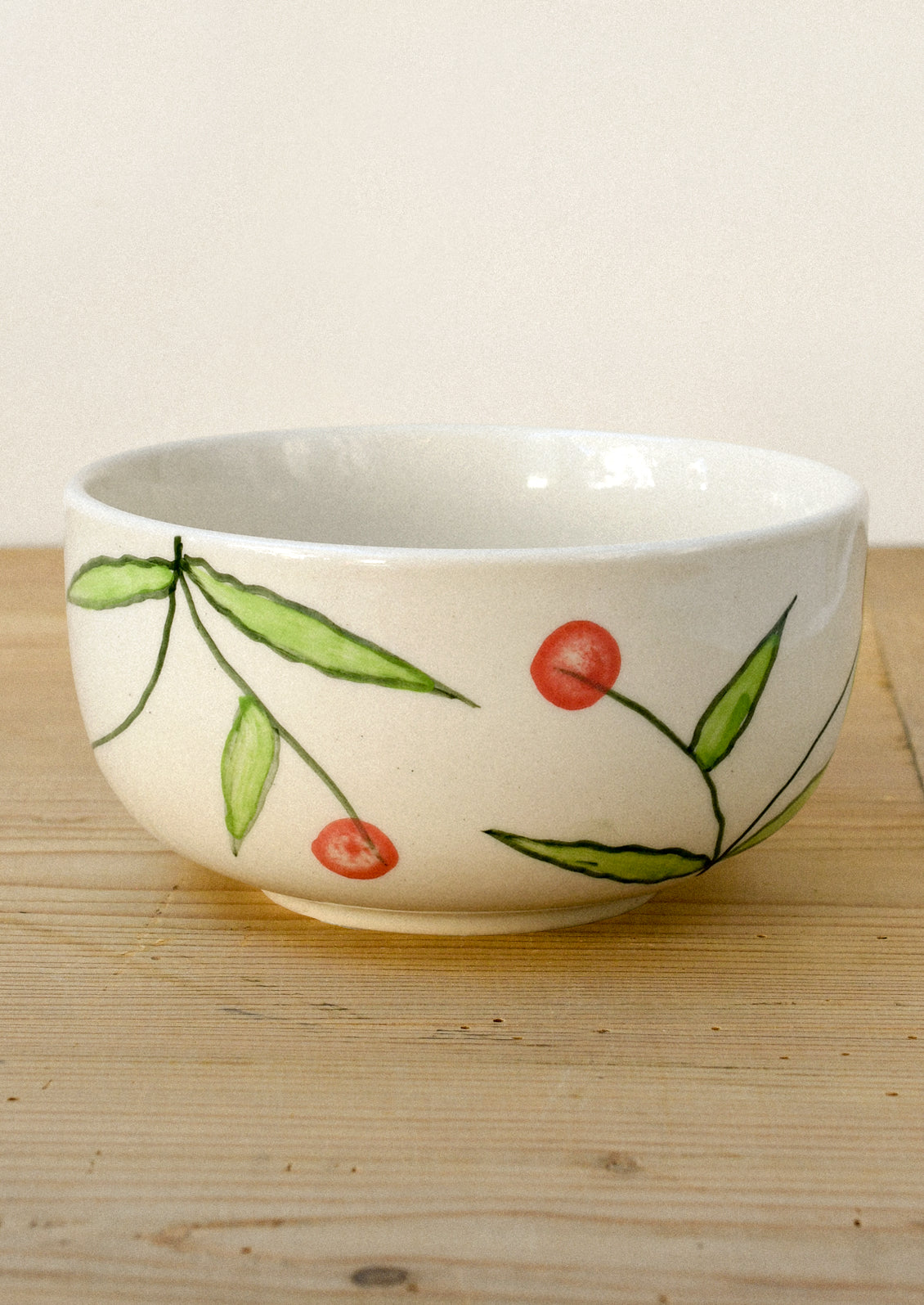 A ceramic bowl with a hand drawn illustration of red cherries.