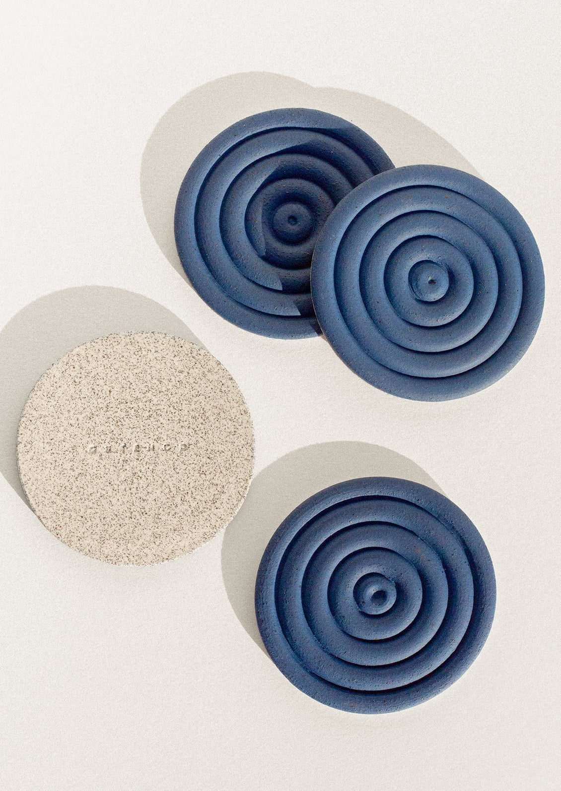 Handmade speckled ceramic coasters with a concentric design in cobalt blue.