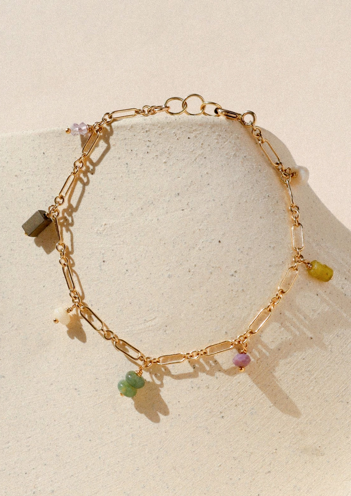 A gold chain bracelet with various colored gems.