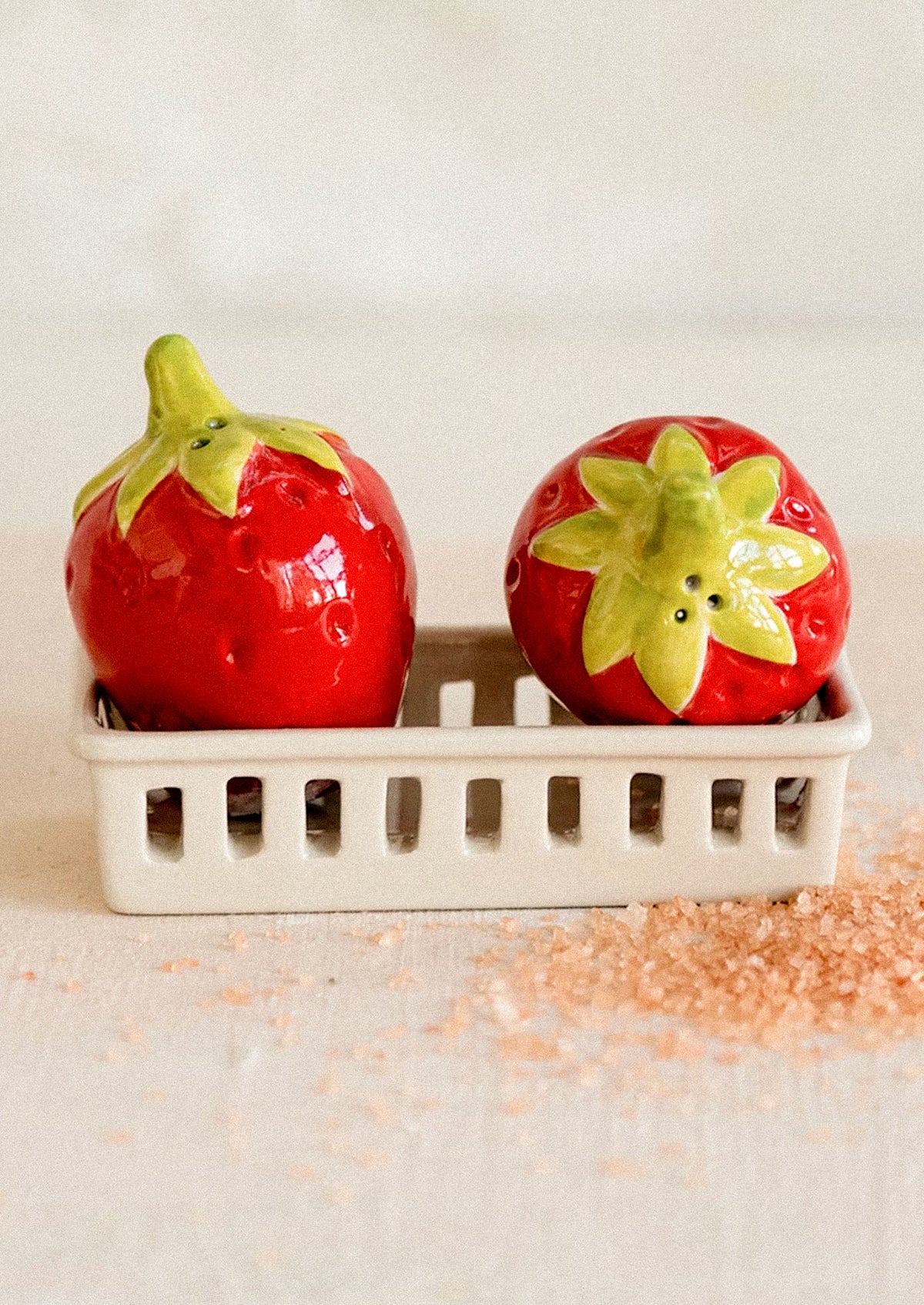 A salt and pepper shaker set depicting red strawberries in a white berry basket.