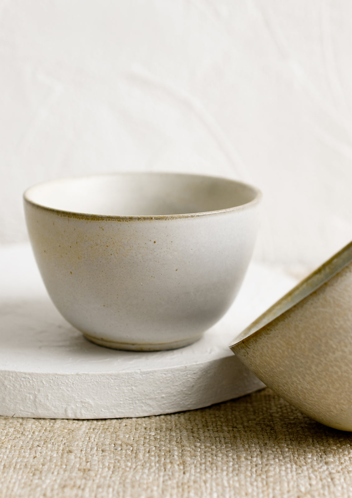 Two small ceramic bowls in natural speckle glazes.