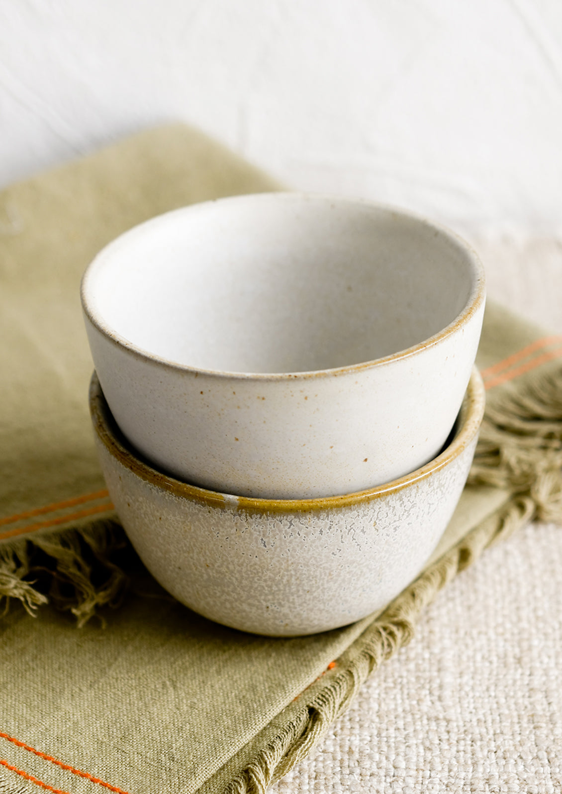 Two small ceramic bowls in natural speckle glazes.
