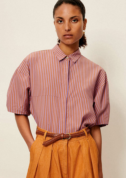 A woman wearing a short collared shirt in orange and purple stripes.