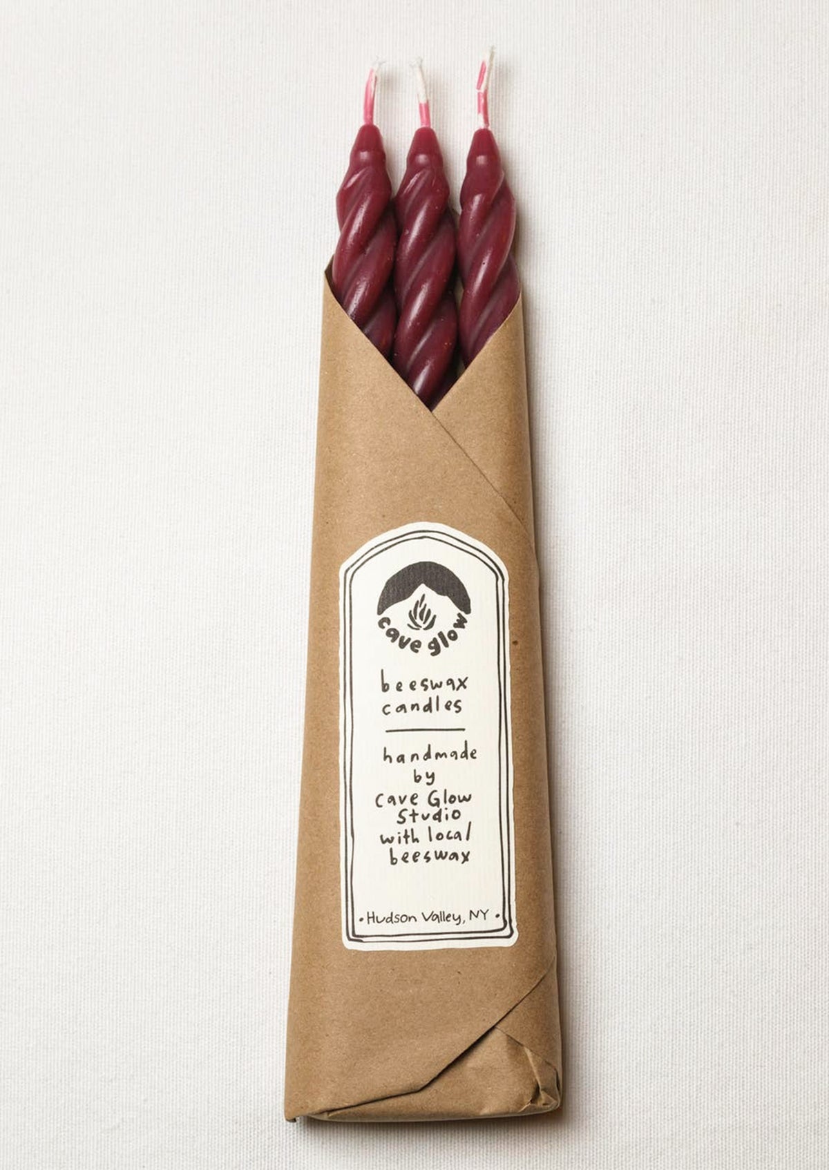 A set of three spiral textured taper candles in dark red color.