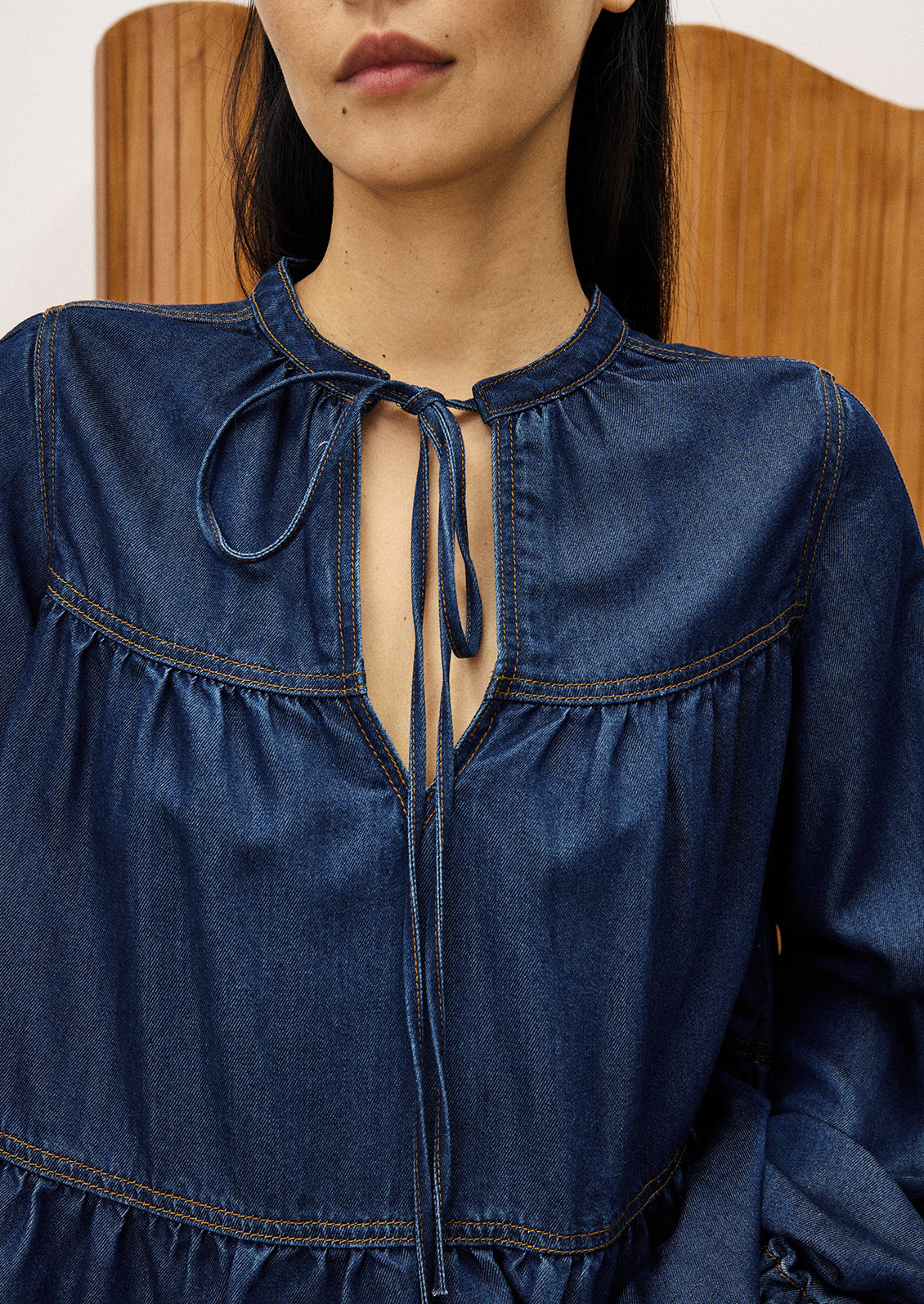 A woman wearing a denim top with shirred ruching.