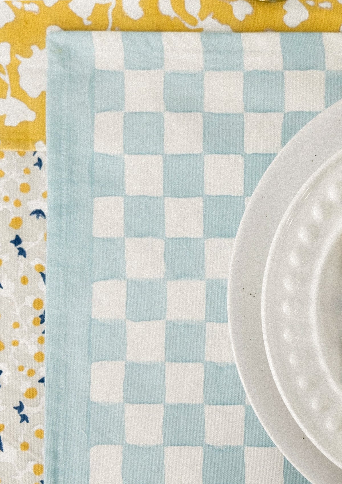 A block printed placemat with checkered pattern in sky blue.