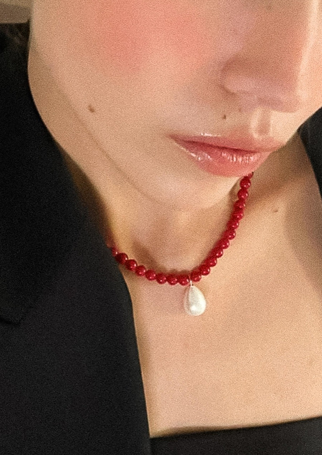 A red beaded necklace with silver hardware and pearl charm.
