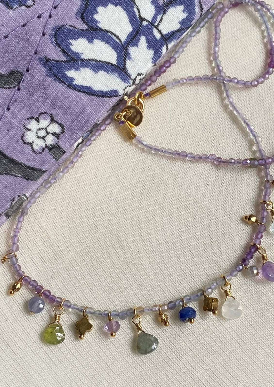 A purple gemstone beaded necklace with assorted gemstone charms.