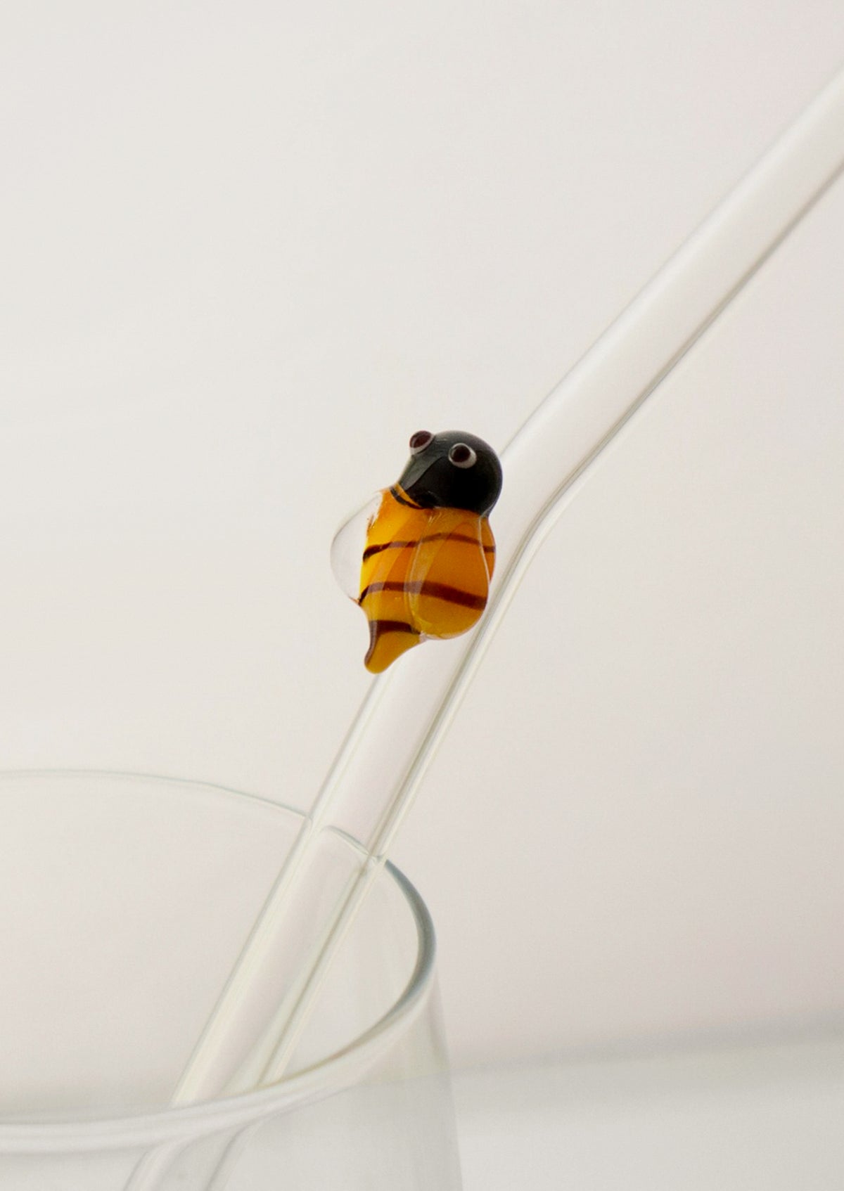 A clear glass straws with bent shape, with lampwork bee figurine.
