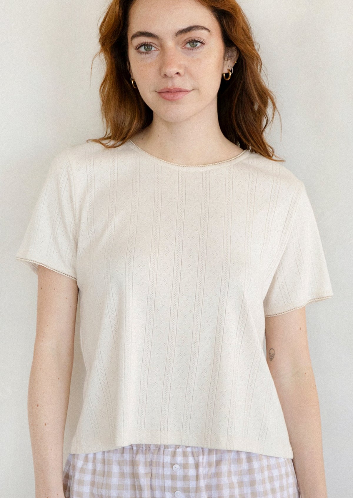 A woman wearing a pointelle stitch tee in cream.