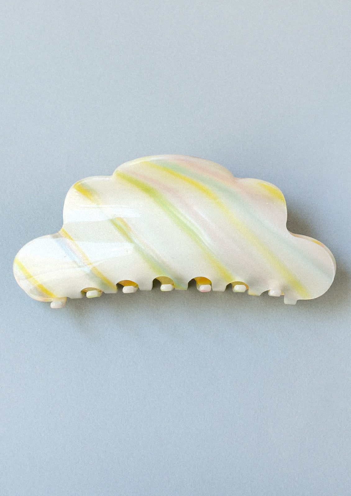 A hair claw clip in the shape of a cloud with pastel colored brush strokes.