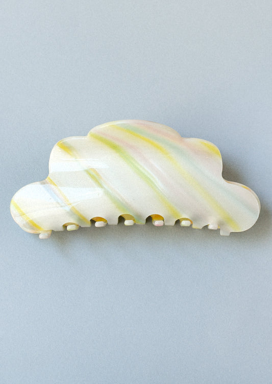 A hair claw clip in the shape of a cloud with pastel colored brush strokes.