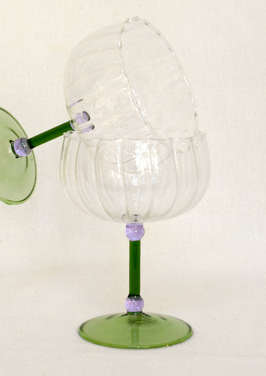 Two clear glass coupes with small round purple details and a green stem and base stacked on top of each other.