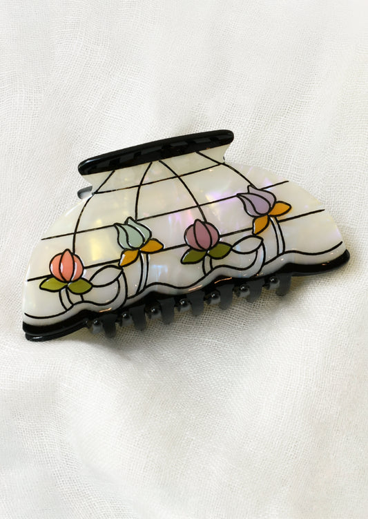 A hair claw shaped like a lamp shade with colorful florals and a grid pattern.
