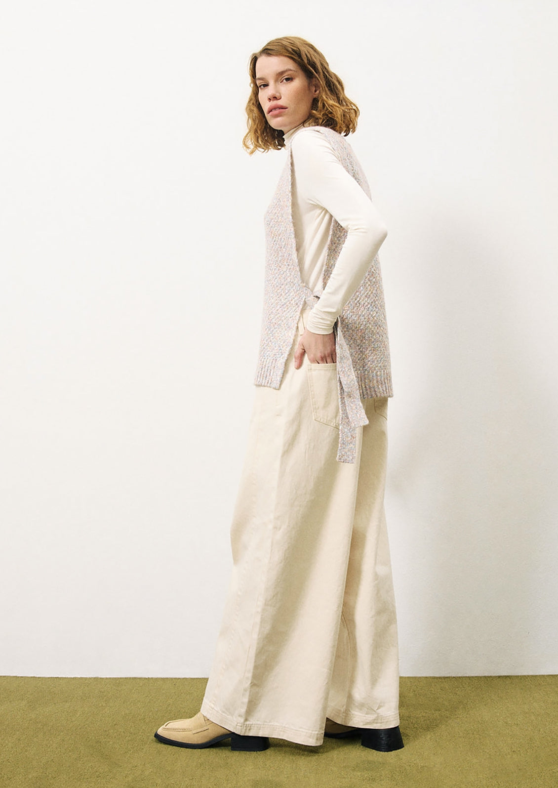 A woman wearing a long tunic style sweater vest in pastel yarn.