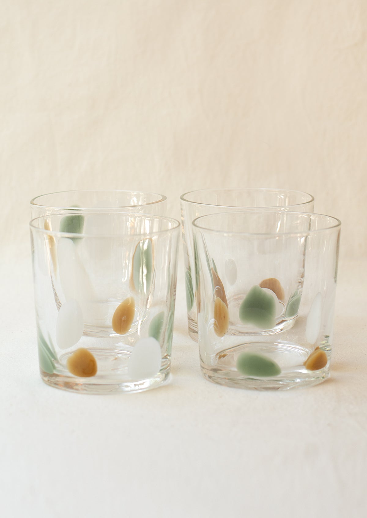 A stack of clear glass tumblers with mint, brown and white speckle pattern.