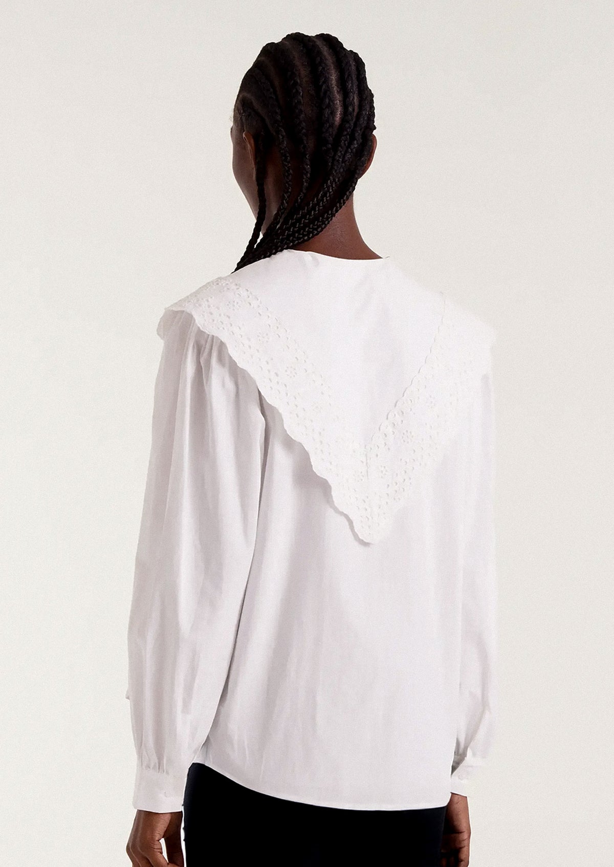 White blouse with intricate collar design worn by a person.