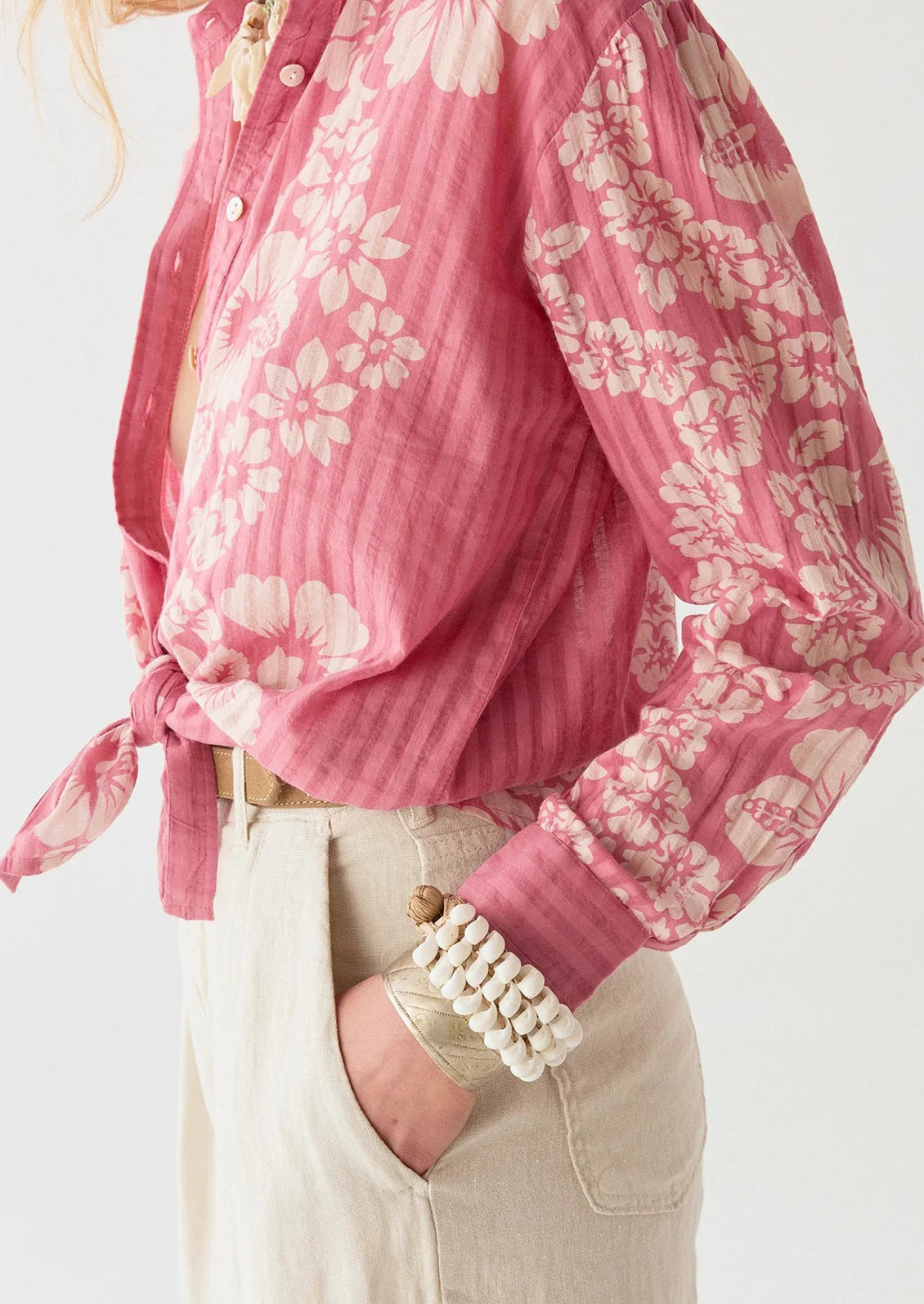 A person wearing a pink cotton shirt with tonal pinstripes and Hawaiian floral pattern.