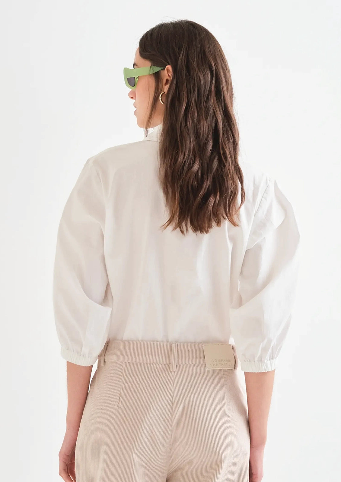 A person wearing a white shirt with multicolor beaded buttons.